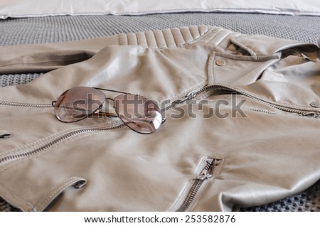 sunglasses with brown jacket on bed in bedroom