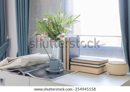 tea cup on book with vase of flower on white desk at home
