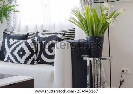 black and white pillows on white sofa with vase of plant in living room
