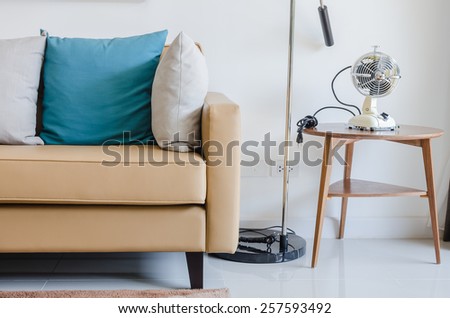 modern sofa with pillows and classical electric fan on wooden round table at home