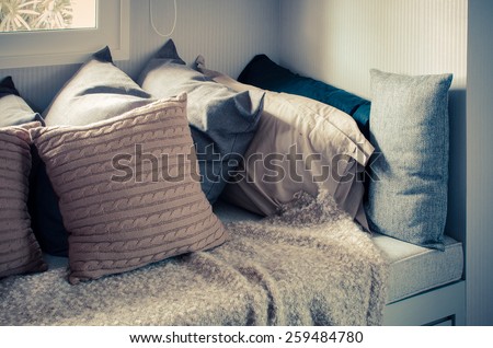 many of pillows on sofa with blanket in living room at home - vintage style effect picture