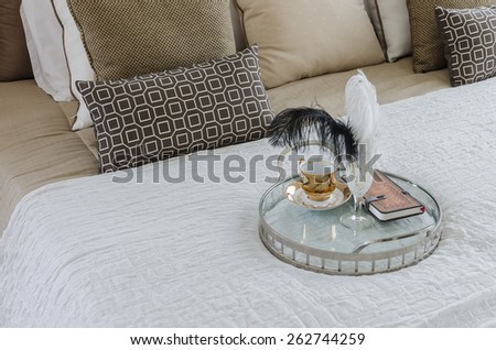 round glass tray of cup and book on bed at home