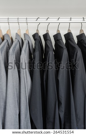 row of black and grey shirts hanging on coat hanger in white wardrobe