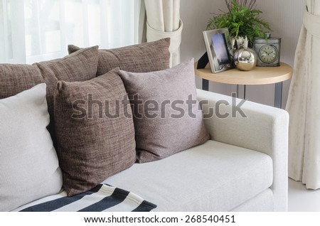 white sofa with brown pillows and wooden round table in living room at home