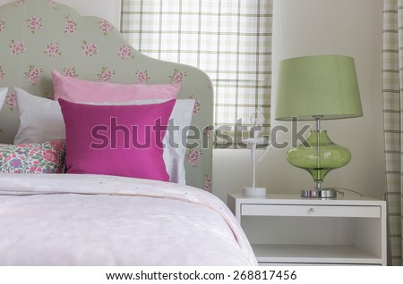 girl\'s bedroom with pink pillow on green bed and green lamp