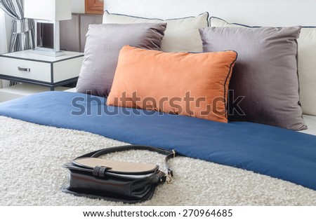 modern bedroom with colorful pillows and female\'s bag on bed at home