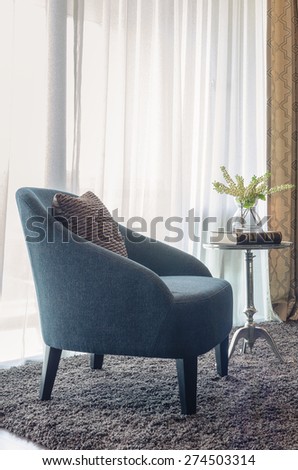 modern blue chair with brown pillow on carpet in living room