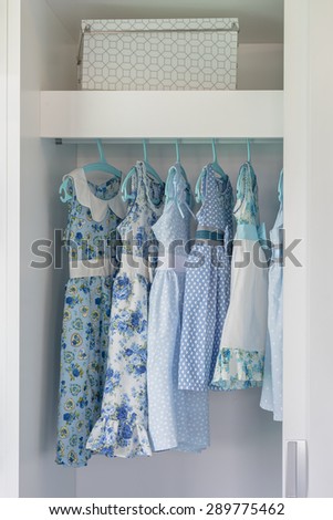 blue color tone girl's dress hanging in white wardrobe