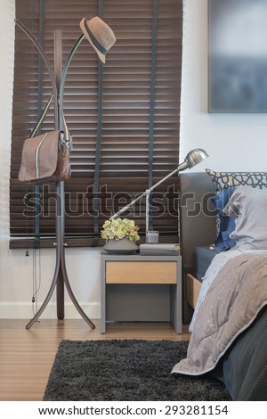 hat and bag hanging on clothes hanger rack with modern lamp in bedroom