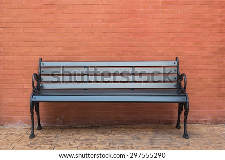 black wooden classic bench with brick wall on concrete floor