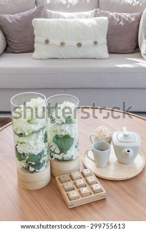 glass vase of plants and tea cup set on wooden round table in living room