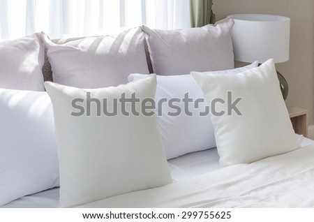 white pillows on modern white bed with lamp at home