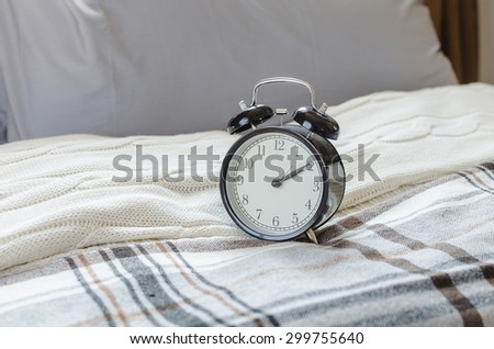modern black alarm clock on bed in bedroom at home