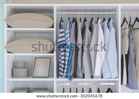 clothes hanging in white wardrobe with pillows and boxes