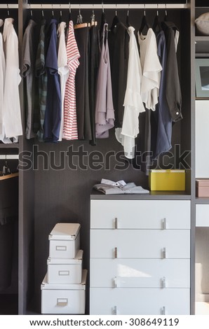 dark color scheme modern walk in closet design with clothes hanging