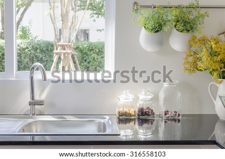 modern sink on black kitchen counter with vase of plant