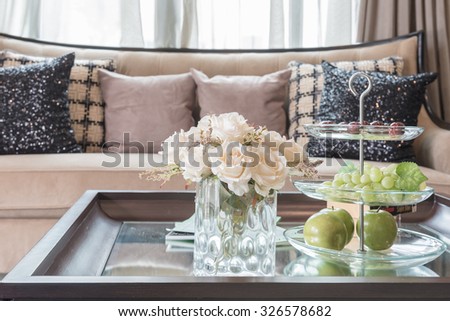 glass vase of flower on wooden table in living room with blur background effect