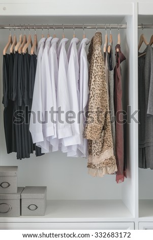 pants, shirts and dress hanging in white wardrobe