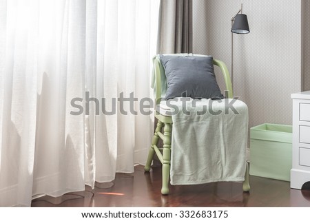 green wooden chair with grey pillow and green blanket in bedroom