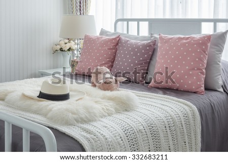 pink pillows with pink doll on white wooden bed and classic hat in bedroom