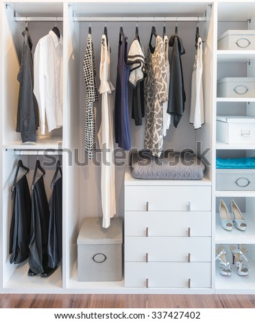clothes hanging on rail in white wardrobe with box and shoes