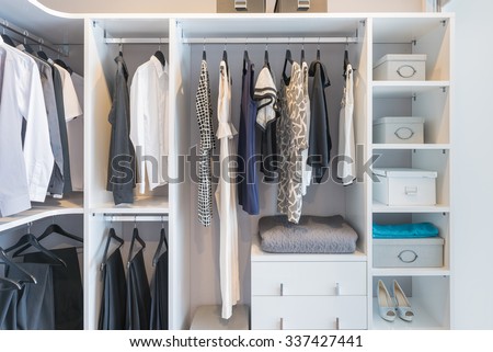 clothes hanging on rail in white wardrobe with box and shoes