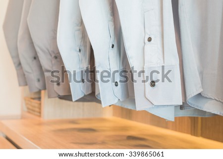 shirts hanging on rack in wooden wardrobe with buttons