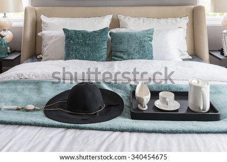 black hat and black tray of coffee cup set on green blanket in luxury bedroom at home