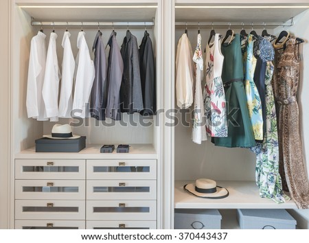 shirts and dress hanging on rail in wooden wardrobe at home