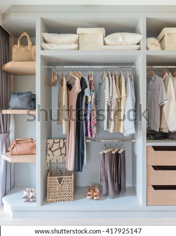 white wardrobe with shirts and pants hanging on rail
