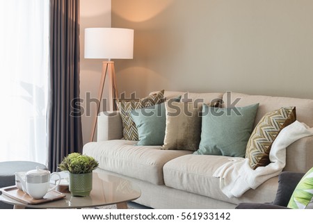 modern living room with green pillows on cozy sofa and wooden lamp, interior design