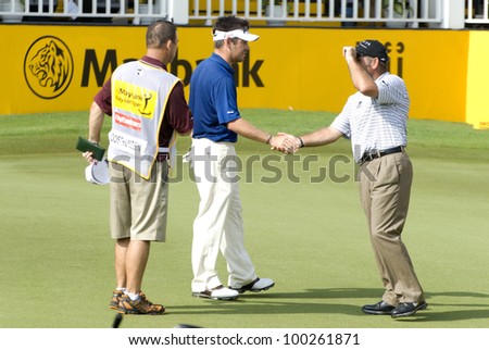 KUALA LUMPUR-APRIL 15: Louis Oosthuizen, center, of South Africa shake hands his compatriot, Hennie Otto after finish the 18th holes during 3rd round match of Maybank Malaysian Open on April 14, 2012