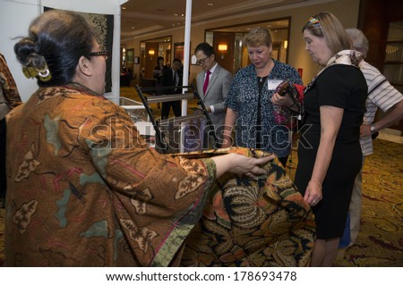 KUALA LUMPUR, MALAYSIA-JUNE 6,2013:Meike Sahala(L) explaining about batik to delegates in exhibition during Global Summit of Women 2013 in Kuala Lumpur, Malaysia on June 6, 2013.