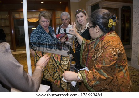 KUALA LUMPUR, MALAYSIA-JUNE 6,2013:Meike Sahala(R) expalining about batik to delegates in exhibition during Global Summit of Women 2013 in Kuala Lumpur, Malaysia on June 6, 2013.