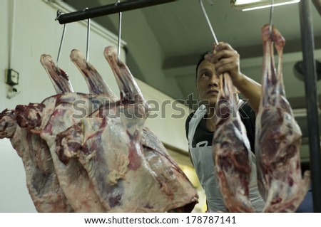 KUALA LUMPUR, MALAYSIA-FEB 26: Unidentified mutton seller at Chow Kit wet market hanged mutton leg to display for customers in Kuala Lumpur, Malaysia on February 26, 2014