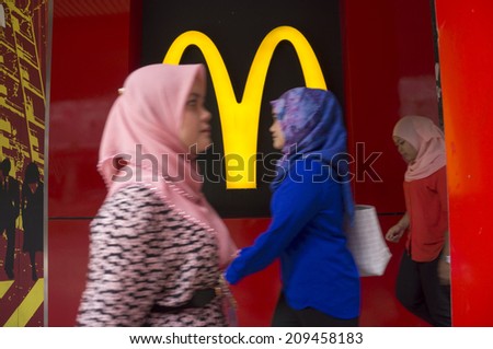 KUALA LUMPUR, MALAYSIA - JULY 22: Unidentified women walk in front of the McDonalds logo at Tun Perak Street, Kuala Lumpur, Malaysia on July 22, 2014.