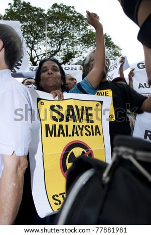 KUALA LUMPUR, MALAYSIA-MAY 20: Demonstrators holds poster during a protest against a proposed rare earth plant to be built in Gebeng, in front of Petronas Twin Towers in Kuala Lumpur May 20, 2011.