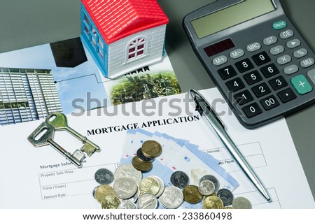 Close view of mortgage application form, house key, ballpoint pen, coins, money and calculator concept