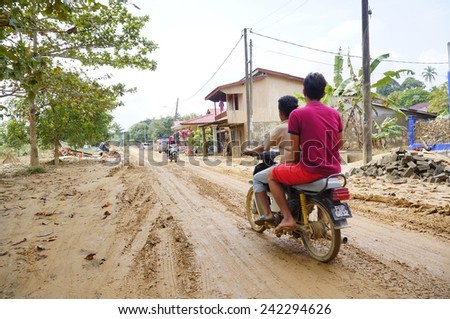 TANAH MERAH, KELANTAN - JANUARY 2: Teenager ride motorcycle to see the impact of floods in Kusial Baru village, Tanah Merah, Kelantan on January 2, 2015