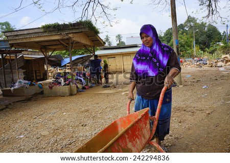TANAH MERAH, KELANTAN - JANUARY 2: Flood victims clean mud with pushchair after floods recede in Kusial Baru village, Tanah Merah, Kelantan on January 2, 2015