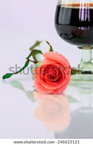 Pink rose and wine in glass on a white background