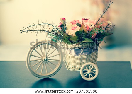 Artificial flowers in a white Bicycle basket  on black table , vintage style