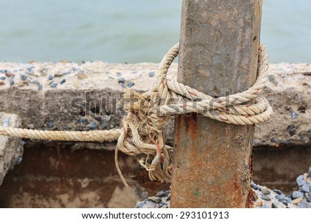 Old fishing boat rope with a Tied Knot around the old concrete post