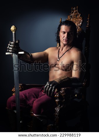 Half-naked man on a throne with a sword in his hand sits deep in thought