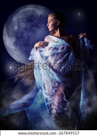 Half-naked girl wrapped in translucent white cloth moves in the light of the full moon