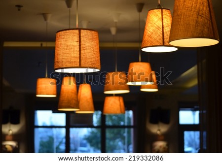 Warm lighting coming out from beautiful lamps on ceiling , against cold lighting from window in a winter day , while taking a hot cup of coffee in a trendy cafe with nice environment