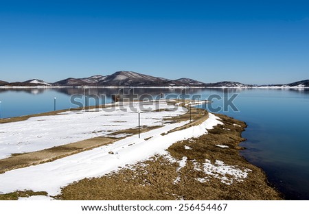 Tranquil scenery.Landscape,Black snowy mountain,clear sky and a water bike on lake at a winter day,Greece