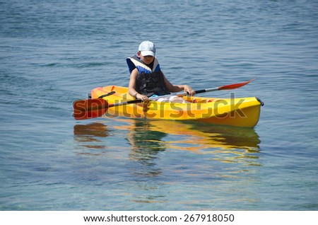 First kayaking lessons. Boy with blue hat and life buoy suit in kayak lessons during summer vacations in an island of Greece