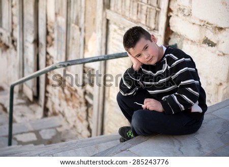 Portrait of a boy in black and white clothes posing,siting in the street of a traditional small street in Syros island,Cyclades, Aegean sea,Greece