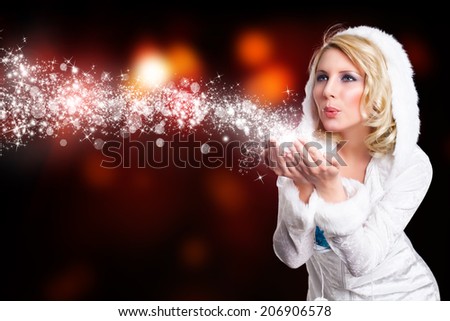 attractive girl in winter outfit blowing twinkling stardust